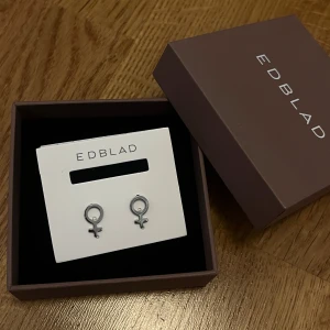 Silverörhängen från Edblad - Säljer ett par stilrena örhängen i silver från Edblad, formade som kvinnosymboler. Perfekta för dig som vill ha ett diskret men ändå statement smycke. Levereras i originalask och de har aldrig används, originalpris 300kr💕