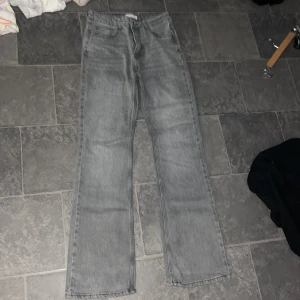 Grå jeans från Gina Tricot - Säljer ett par grå jeans från Gina Tricot i klassisk modell med raka ben och fyra fickor. Jeansen har normal passform och är tillverkade i denim. Perfekta för en avslappnad stil.