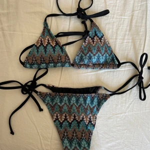 Mönstrad bikini - Säljer en bikini i fint skick med väldigt fint mönster och knytband i svart. Perfekt för stranden eller poolen! Skriv privat vid frågor💙