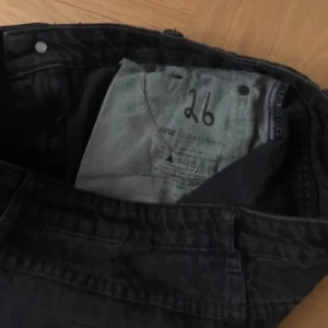 Svart jeanskjol med fransar från One Teaspoon - Säljer en svart jeanskjol från One Teaspoon med fransiga benslut och slitna detaljer både fram och bak. Klassisk femficksmodell och låg midja. Perfekta för en avslappnad stil.💕