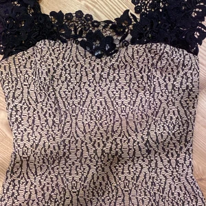 Svart spetsklänning från Oxygene - Säljer en snygg svart spetsklänning från Oxygene i storlek M. Klänningen har vackra blommiga spetsdetaljer upptill och ett figurnära snitt. Mönstret är elegant och materialet känns lyxigt. Perfekt för dig som vill sticka ut!