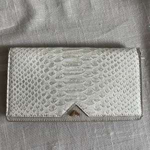 Vit plånbok med ormskinnsmönster - Snygg vit plånbok med ormskinnsmönster. Plånboken har flera kortfack och en dragkedja för mynt. 
