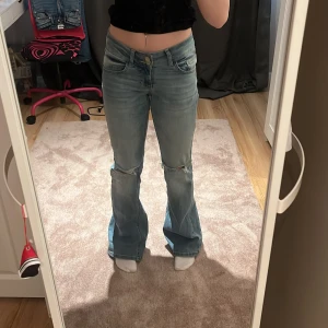 Lågmidjade bootcut jeans med hål - Lågmidjade bootcut jeans med hål på knäna från Nelly! Använda 1 gång och jag säljer då de är lite stora för mig. Innerbenslängden är runt 82-83cm. Jättefina och perfekta till våren! Kostar 699 egentligen så passa på☺️