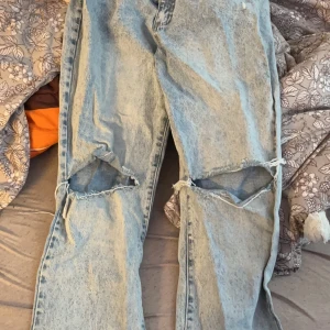 Blå jeans med raka ben från Cotton On - Säljer ett par blå jeans med raka ben från Cotton On. De har en cool slitning vid knäna och en klassisk femficksdesign. Perfekta för en avslappnad stil.