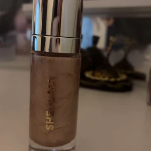 Flytande highlighter från Sheglam - Snygg flytande highlighter från Sheglam i en elegant flaska med silverlock. Perfekt för att ge huden en strålande glöd och definiera ansiktsdrag. Den har en skimrande finish som passar bra för att skapa en glamorös look.