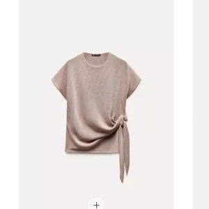 Beige topp med knyt - Snygg beige topp med korta ärmar och en unik knytdetalj på sidan. Perfekt för en stilren look.