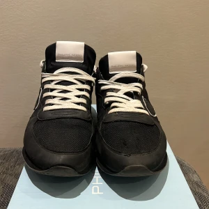 Svarta sneakers från Philippe Model, Ge gärna prisförslag  - Snygga svarta sneakers från Philippe Model med vita detaljer och snörning. Skorna har en stilren design med märkets logga på tungan. Perfekta för en casual look. Skick 8/10