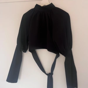 Svart blus med knytband nakd x Hanna schönberg  - Svart topp från NAKD X Hanna schönberg Använd fåtal gånger 