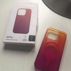 Fodral för iPhone 15 Pro från Ideal of Sweden - Snyggt och färgglatt ombre-fodral för iPhone 15 Pro från Ideal of Sweden. Fodralet har en gradient i rosa och orange och är designat för att skydda din telefon med stil. Perfekt för dig som vill ha något unikt och trendigt.