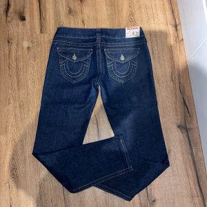 Mörkblå jeans från True Religion - Snygga mörkblå jeans från True Religion med ikoniska bakfickor och kontrastsömmar. Både tjejer och killar kan använde dessa jeans. Nypris går på 1300kr. Säljer de för att dom var lite för baggy för min smak