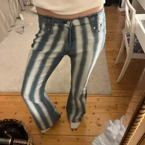 Randiga bootcut jeans - Så coola blå och vita randiga jeans 🪩🌊 Jeansen har klassisk femficksdesign och knappar framtill. Midjemåttet rakt över är 39, midjemåttet runt om är 82/83, innerbensmått är 82 och ytterbensmåttet är 109 cm💕