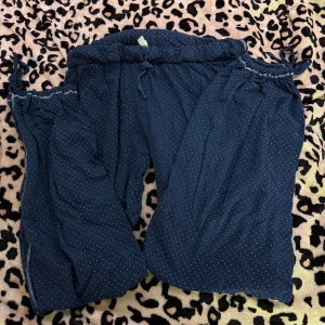 Mörkblå prickiga pyjamasbyxor - Säljer ett par mörkblå pyjamasbyxor med små vita prickar. Byxorna har resår i midjan och vid bensluten för en bekväm passform. Perfekta för en avslappnad stil.