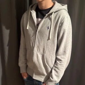 Grå hoodie från Ralph Lauren - Riktigt snygg raffe zip. Väldigt bra skick, storlek S. Köpt för 1500 på ralph lauren outlet i Göteborg. Mitt pris 699