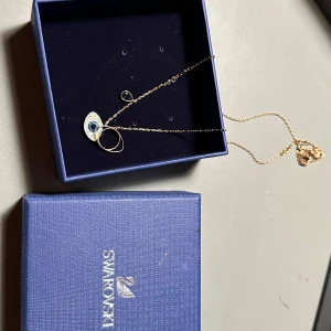 Halsband med öga från Swarovski - Super fint halsband från Swarovski med ett öga som hänge, dekorerat med gnistrande stenar. Hänget har en blå detalj i mitten och en liten droppe på kedjan🥰