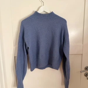 Stickad tröja från & Other Stories - Säljer en snygg blå stickad tröja från & Other Stories som är använd ett fåtal gånger. Tröjan har en hög krage,  långa ärmar och en snygg passform. Storlek XS men passar även S. Superfin färg nu till våren 😍