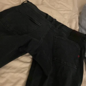 Svarta jeans från Replay - Snygga svarta jeans från Replay med klassisk femficksdesign. De har en knappgylf och är tillverkade i ett slitstarkt material. Perfekta för en stilren look.