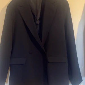 Mörkblå kavaj från Cubus  - Elegant mörkblå kavaj från Cubus. Kavajen har en klassisk design med knappar framtill och fickor med lock. Perfekt för en stilren look. Lite fina kavaj som är perfekt över studentklänning eller andra tillställningar. Tyvärr är den alldeles för lite för mig och därav säljer nu.