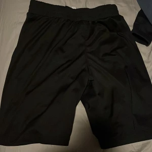 Svarta träningsshorts - Snygga svarta träningsshorts från Energetics. Perfekta för gymmet eller löprundan. De har en elastisk midja för extra komfort och är tillverkade i ett lätt och andningsbart material.
