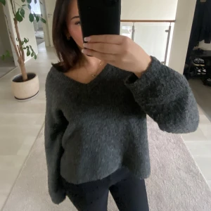 Mörkgrå stickad tröja - Säljer en mysig mörkgrå stickad tröja med v-ringning. Tröjan har en lös passform och långa ärmar. Den är enkel att matcha med olika outfits och ger en avslappnad look. Från JDY💞