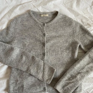 Grå kofta från Gina Tricot - Mysig grå kofta från Gina Tricot i storlek XS. Den har en klassisk design med knappar framtill och långa ärmar. Perfekt för kyligare dagar och enkel att matcha med olika outfits.