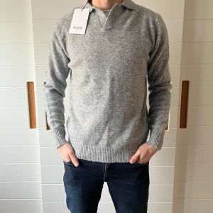 Grå tröja från Selected Homme - Säljer en stilren grå tröja från Selected Homme. Tröjan har en klassisk design med krage och långa ärmar. Perfekt för en avslappnad men ändå snygg look. Passar bra till jeans eller chinos.