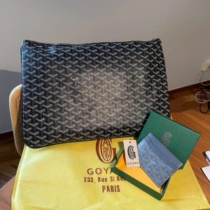 Svart mönstrad datorväska & plånbok  - Säljer en stilren svart datorväska. Väskan har en praktisk dragkedja och är perfekt för att bära med sig det viktigaste. Även en stilren grå plånbok!