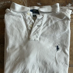 Vit pikétröja från Ralph Lauren - Säljer en klassisk vit pikétröja från Ralph Lauren i custom slim fit. Piken e sjukt enkel att få in i vilken outfit som helst och är i fantastiskt skick. Nypris, 1500, pris nu, 200. Hör bara av dig vid frågor!
