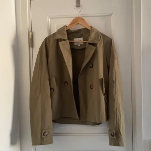 Khaki grön trenchcoat från ONLY - Skitsnygg khaki grön trenchcoat från ONLY med dubbelknäppning. Jackan har används ett par gånger och väljer därför att sänka priset rehjält utifrån det ursprungliga priset!! Den är mittemellan kort och normal lång i längden och ärmarna skulle jag säga är lite längre🩷