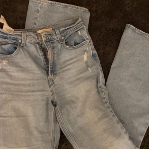 Ljusblå jeansbyxor - Snygga ljusblå jeansbyxor med slitningar för en trendig look från Levi's. De har en klassisk femficksdesign och dragkedja. Perfekta för en avslappnad stil.