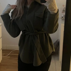 Olivgrön kappa med bälte - Snygg olivgrön kappa med bälte i midjan och stora knappar framtill. Jackan har långa ärmar och en klassisk krage, sååå fin, ingen defekt alls och har använts både vår och höst och är den perfekta jackan, men tyvärr så har jag tröttnat lite på den och köpt en ny :( . Sitter som en S ! sänker pris vid snabb affär 😻