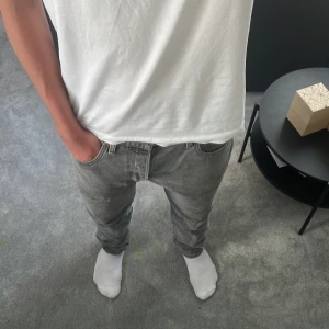 Grå Levis 501 jeans straight fit - Säljer ett par grå Levis 501 jeans med klassisk straight fit och normal passform. Jeansen har fem fickor, knappgylf och den ikoniska Levis-lappen bak. Perfekt tvättad grå färg som funkar till allt. Materialet är slitstarkt bomullsjeans. Storlek W33 L34