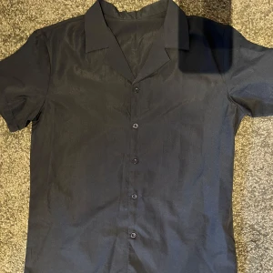 Kortärmad skjorta  - Lätt, stilren och otroligt bekväm – den här kortärmade skjortan är din nya favorit för varma dagar. Perfekt för både vardag och semester, med ett snyggt snitt som passar alla tillfällen. Skjortan har en klassisk krage och knäppning framtill. Passar lika bra på stranden som på after worken. Matcha med chinos, jeans eller shorts för en komplett look.