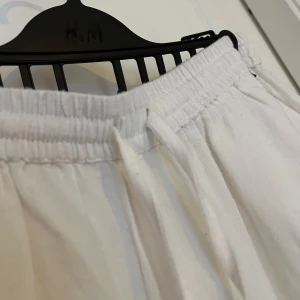 Vita linnebyxor från Nelly - Säljer ett par vita linnebyxor från Nelly i storlek 34. Byxorna har resår och snörning i midjan för en skön och avslappnad passform. Perfekta för chill dagar eller när du vill vara bekväm men ändå se fräsch ut.