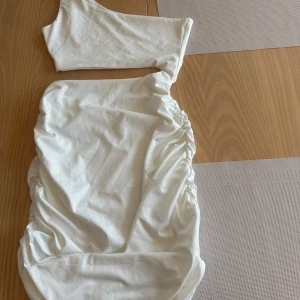 Vit one shoulder kortklänning - Snygg vit kortklänning med one shoulder-design och rynkade sidor. Klänningen har en tight passform. Shein och helt oanvänd!