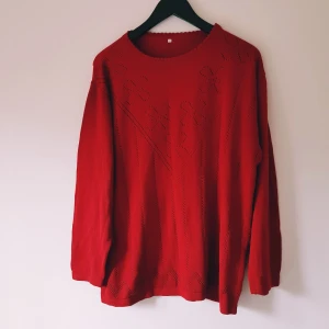 Röd stickad långärmad tröja strl 42 - Röd stickad tröja med lång ärm och snygga hålmönster framtill som skapar ett unikt uttryck. Rund halsringning och mjuk känsla, perfekt för dig som gillar färg och vill sticka ut lite extra.  Hål & noppror (se extra bilder) annars fint skick