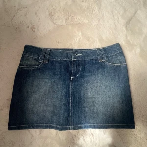 Blå jeanskjol från ONLY, storlek 38 - Snygg blå jeanskjol från ONLY i klassisk modell med fem fickor, bälteshällor och tydliga sömmar. Kjolen är kort och har en rak passform som passar perfekt till sneakers eller boots. Perfekt för dig som gillar en tidlös denimlook.