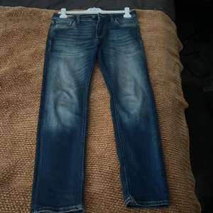 Blå jeans från Jack & Jones -  blå jeans från Jack & Jones med en klassisk straight fit. Återpublicering av denna produkt alltså att jag köpt på plick men inte använder. Så tar plick bilderna/text  från förra ägaren hade på sin annons och skapar en ny annons för mig med d bilder och text. (Tagit bort Texten)