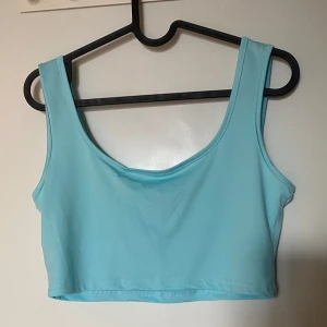 Ljusblå croppad linnetopp  - Säljer en ljusblå croppad linnetopp från SHEIN. Toppen är ärmlös med breda axelband och har en enkel, stilren design. Tillverkad i mjuk och stretchig polyesterblandning som sitter skönt på kroppen. Perfekt för varma dagar eller som layering-piece. Frakt tillkommer