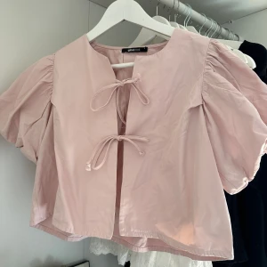 Ljusrosa blus med puffärm Gina Tricot - Supersöt ljusrosa blus från Gina Tricot med puffiga korta ärmar och två knytband framtill. 