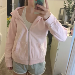 Ljusrosa hoodie från 157 med dragkedja - Mysig ljusrosa hoodie från 157 med dragkedja framtill och två stora fickor. Tröjan har huva och är långärmadr. Tillverkad i mjuk bomull som känns skön mot huden.💞