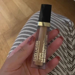 Estée Lauder Futurist Concealer 4N - Estée Lauder Futurist Soft Touch Brightening Concealer i nyansen 4N. Kommer i en stilren fyrkantig tub med svart lock och gulddetaljer. Perfekt för att ljusa upp och täcka mörka ringar under ögonen eller ojämnheter i ansiktet.