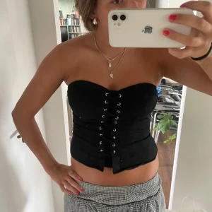 Svart korsett-topp  - As cool svart korsett-topp från H&M Divided med snörning framtill och dragkedja i ryggen. 