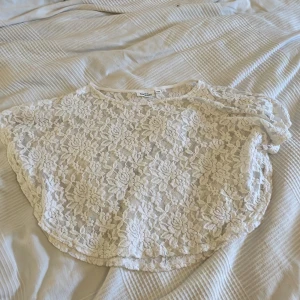 Vit spetsponcho/blus från KappAhl - Superfin vit blus/poncho från KappAhl i spets med blommigt mönster. 
