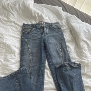 Lågmidjade jeans med detaljer - Så snygga lådmidjade jeans med massa fina detaljer. Passar mig som har 27/32 i jeans och är 160 men lite långa på mig. Midjemått: 40 cm, längd: 103 cm (om jag ens räknar rätt haha)