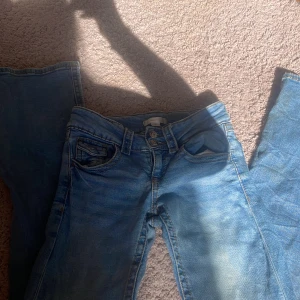 Blå bootcut jeans från Gina Tricot, stl 152 - Snygga blå jeans från Gina Tricot i storlek 152. Klassisk femficksmodell med orangea kontrastsömmar och knappgylf. Jeansen har en rak passform och är tillverkade i mjukt denimtyg som är skönt att bära hela dagen.