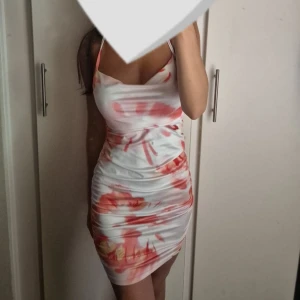 Vit och röd tight kortklänning - Säljer en superfin kort klänning med smala axelband och figurnära passform. Passar super att ha i ett varmt ställe! 