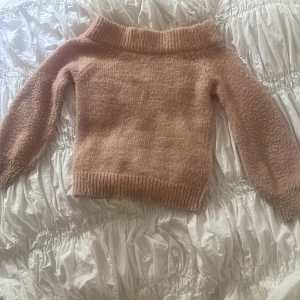 Beige stickad tröja från Gina Tricot - Supermysig beige stickad tröja från Gina Tricot med bred ribbad krage och långa ärmar. Tröjan har en lite loose passform och är perfekt för lager-på-lager. Materialet är fluffigt och mjukt, vilket gör den extra skön att ha på sig. Den är tyvvär lite nopprig på ärmarna