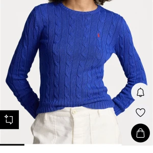 Blå kabelstickad tröja från Ralph Lauren - Säljer en blå kabelstickad tröja från Ralph Lauren med rund halsringning och lång ärm. Tröjan har det klassiska röda broderade logotypen på bröstet och ribbade muddar. Perfekt för dig som gillar preppy stil och vill ha något snyggt och bekvämt.