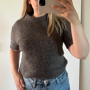 Brun stickad tröja från Gina Tricot - Kortärmad brun stickad tröja från Gina Tricot. Tröjan har en rund halsringning och är gjord i ett mjukt material. Perfekt att styla med jeans eller kjol.