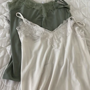 OBS BARA DET GEÖNA KVAR - 1 linnetopp från Amisu i storlek XS. En är ljusbeige med vit spetskant och tunna axelband, den andra är olivgrön med matchande spets. Båda har v-ringning och mjukt, slätt tyg som känns lyxigt. Perfekta för lager-på-lager eller som statement-piece.
